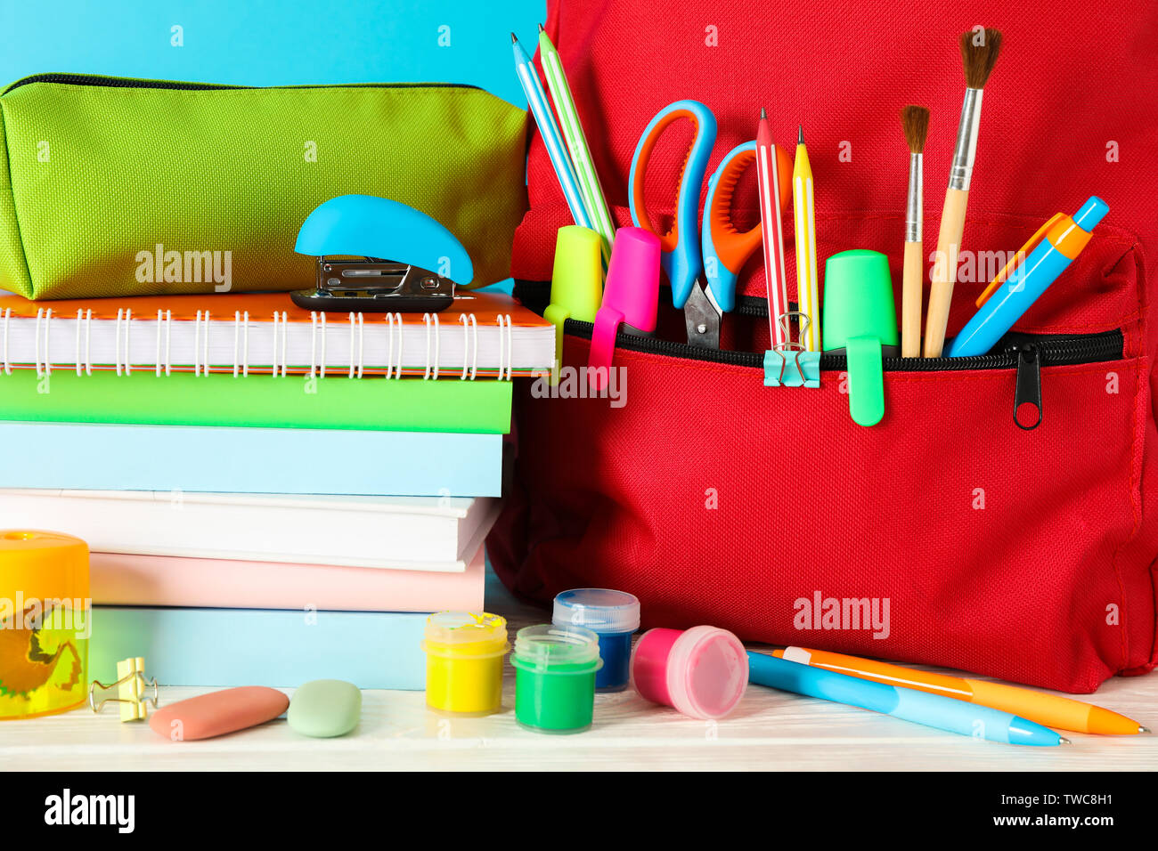 La scuola fornisce su un tavolo di legno contro il colore di sfondo e primo piano Foto Stock