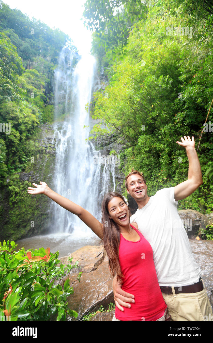 Hawaii tourist gente giovane felice da cascata durante il viaggio sulla famosa strada di Hana a Maui, Hawaii. Ecoturismo Concetto di immagine con happy backpackers. Interracial Asian / Caucasian coppia giovane. Foto Stock