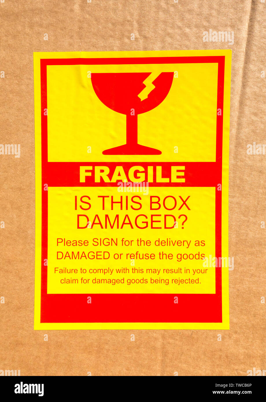 Un rosso e giallo appiccicoso etichetta di spedizione attaccato ad una scatola di cartone, consegnati tramite corriere, con le principali parole: Fragile - è questa casella è danneggiato? Foto Stock