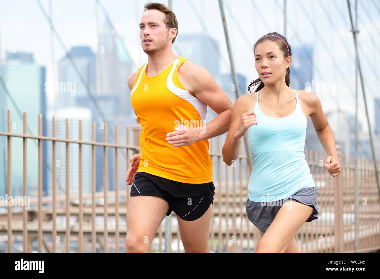 Esecuzione di giovane jogging la formazione per la maratona di New York. Guide su eseguire all'esterno. Donna asiatica e uomo caucasico runner fitness e modelli sport jogging sul ponte di Brooklyn, New York City, Stati Uniti d'America. Foto Stock