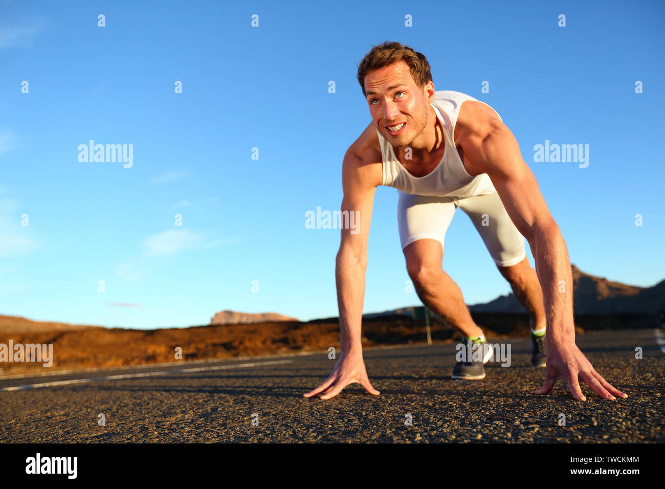 Sprinter a partire sprint - running man ottenere pronto per iniziare a correre in volata. Montare maschio atleta runner di formazione al di fuori sulla strada in un bellissimo paesaggio di montagna la natura. Foto Stock