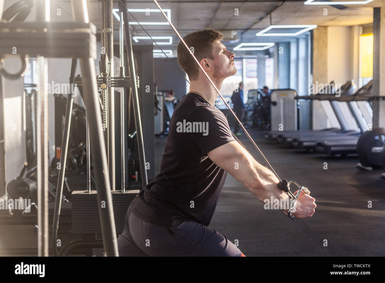 Vista laterale close up ritratto di giovane adulto fiducioso crossfit man standing e facendo trx esercizi in palestra da soli, formazione torace, allenamento sul ring. Foto Stock