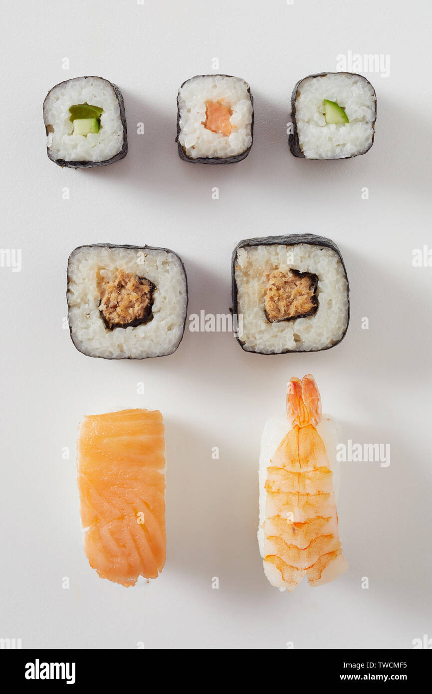 Un assortimento di sushi fresco disposti su bianco con materie salmone Nigiri, gamberi o sashimi di aragosta e rotoli maki con nori alghe marine Foto Stock