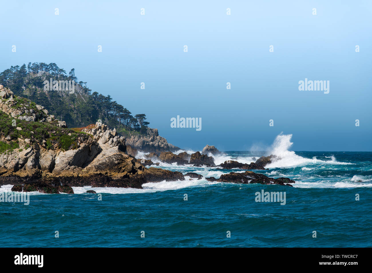 Grandi onde si infrangono contro le rocce e dirupi del punto Lobos sotto una nebbia e cielo nebbioso vicino Carmelo, California Foto Stock