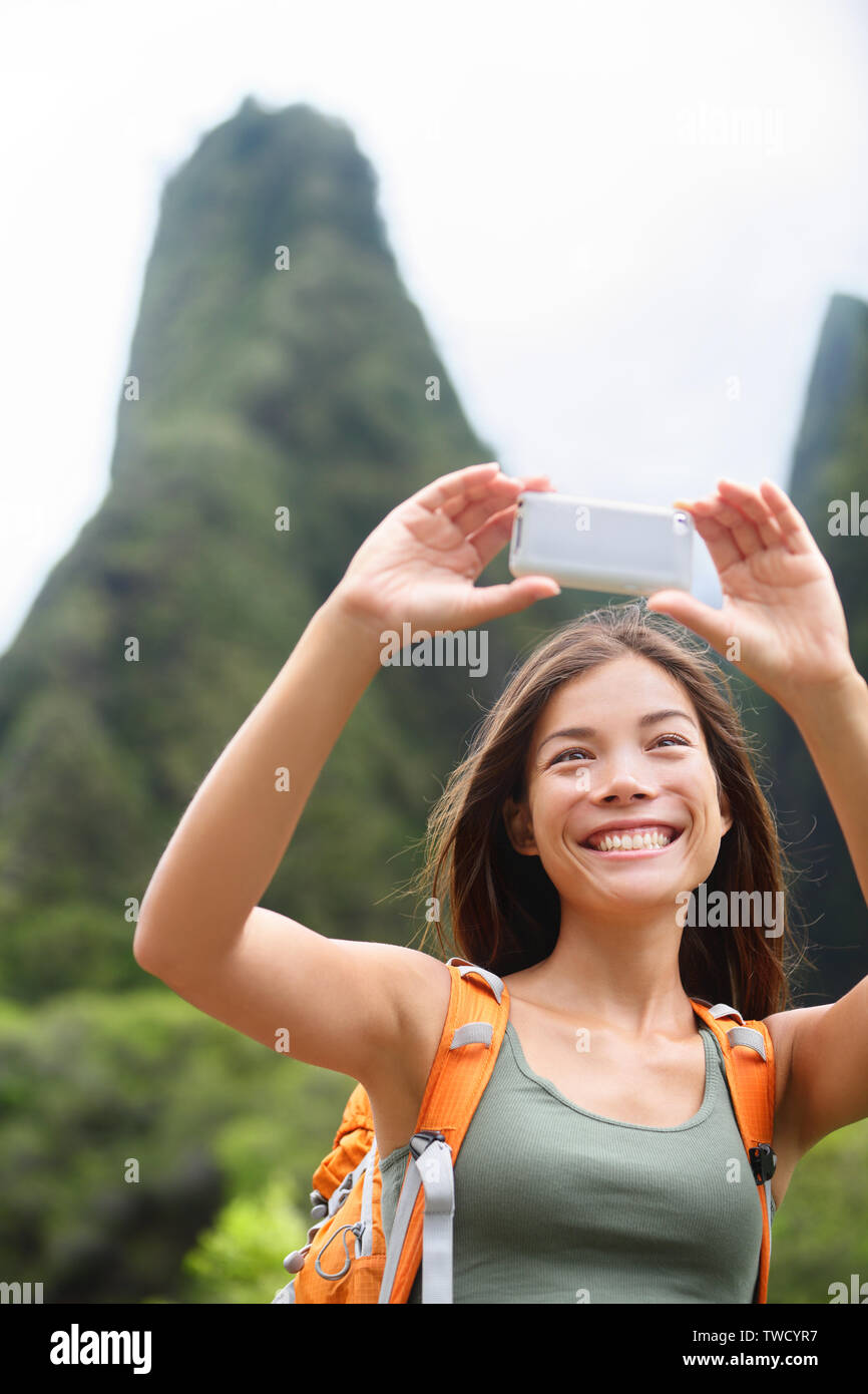 Donna escursionista tenendo selfie foto utilizzando smartphone durante le escursioni su Hawaii godendo di attività all'aperto. Donna escursionista prendendo foto con smart phone fotocamera. Iao Valley State Park, Wailuku, Maui, STATI UNITI D'AMERICA. Foto Stock