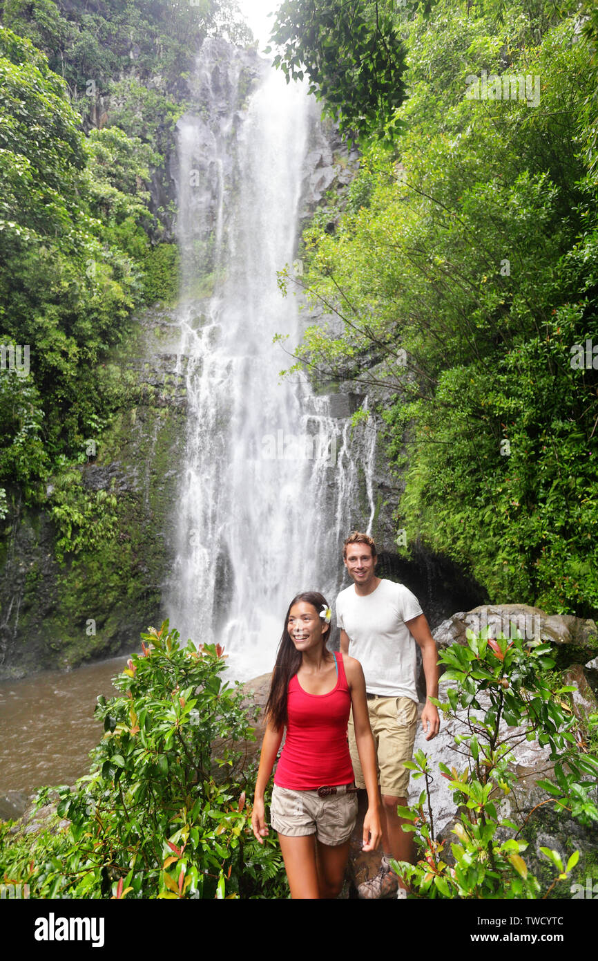 Hawaii escursioni turistiche persone. Coppia felice da cascata durante la marcia su strada a Hana a Maui, Hawaii. Ecoturismo Concetto di immagine con happy backpackers. Interracial Asian / Caucasian coppia giovane. Foto Stock