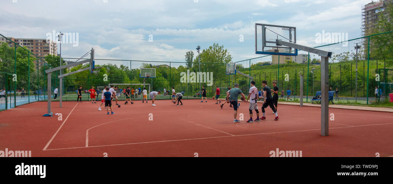 Teen boys praticano la loro basketballs si muove con la guida di un autobus, in Parcul Lumea Copiilor, Mondo bambini Park, nel centro di Bucarest. Foto Stock