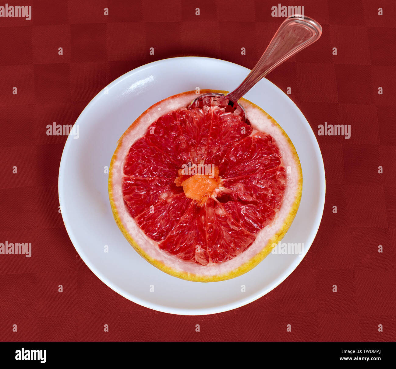 Una metà di un pompelmo su un disco bianco e lo sfondo rosso Foto Stock