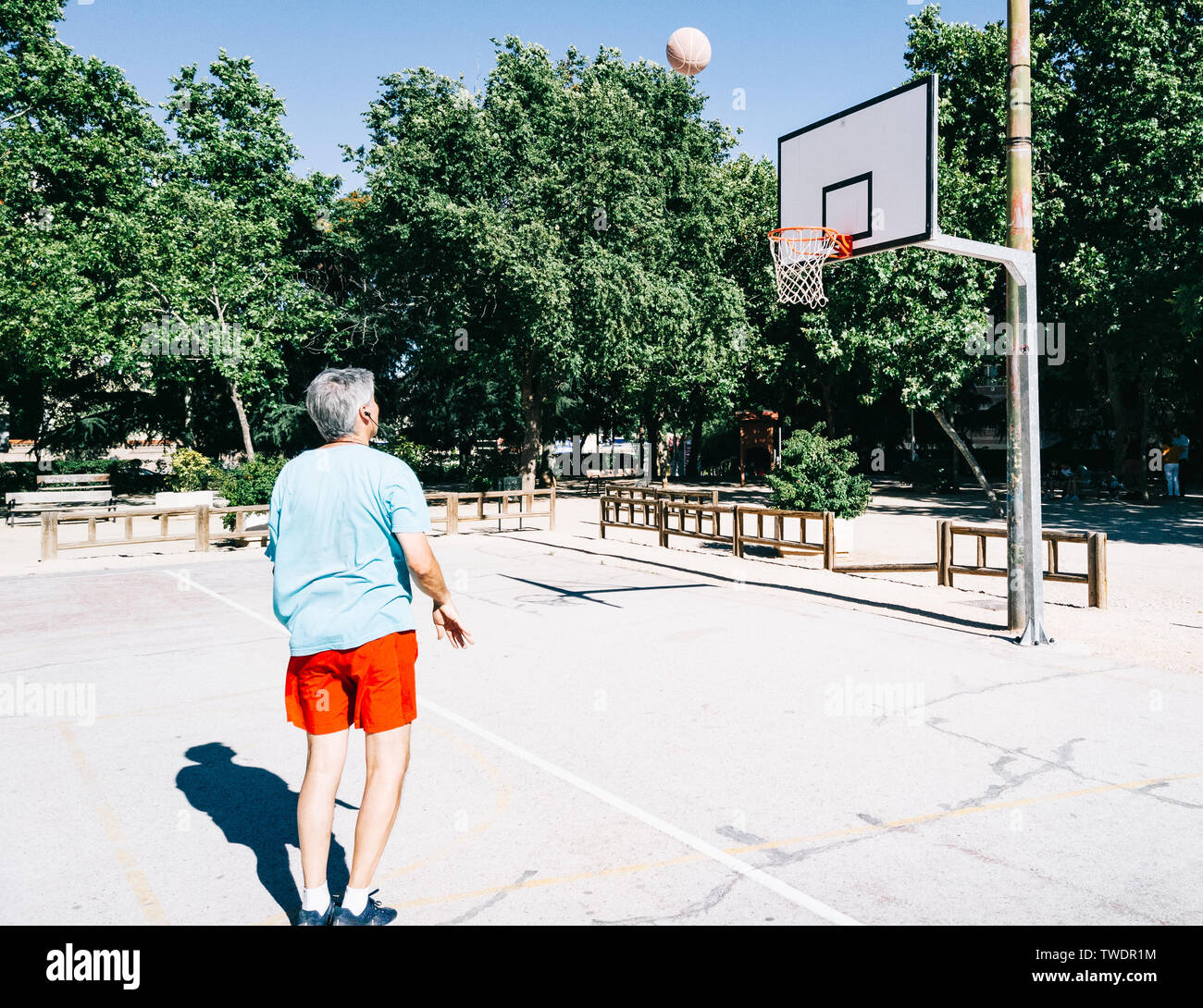 Il vecchio uomo giocando e cesto di coaching da solo in un campo di pallacanestro Foto Stock