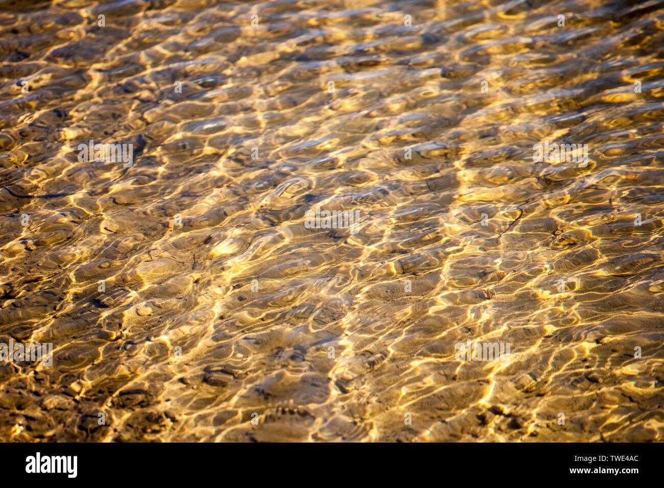 Acqua ondulata disegno superficiale di colore giallo con fondo sabbioso Foto Stock