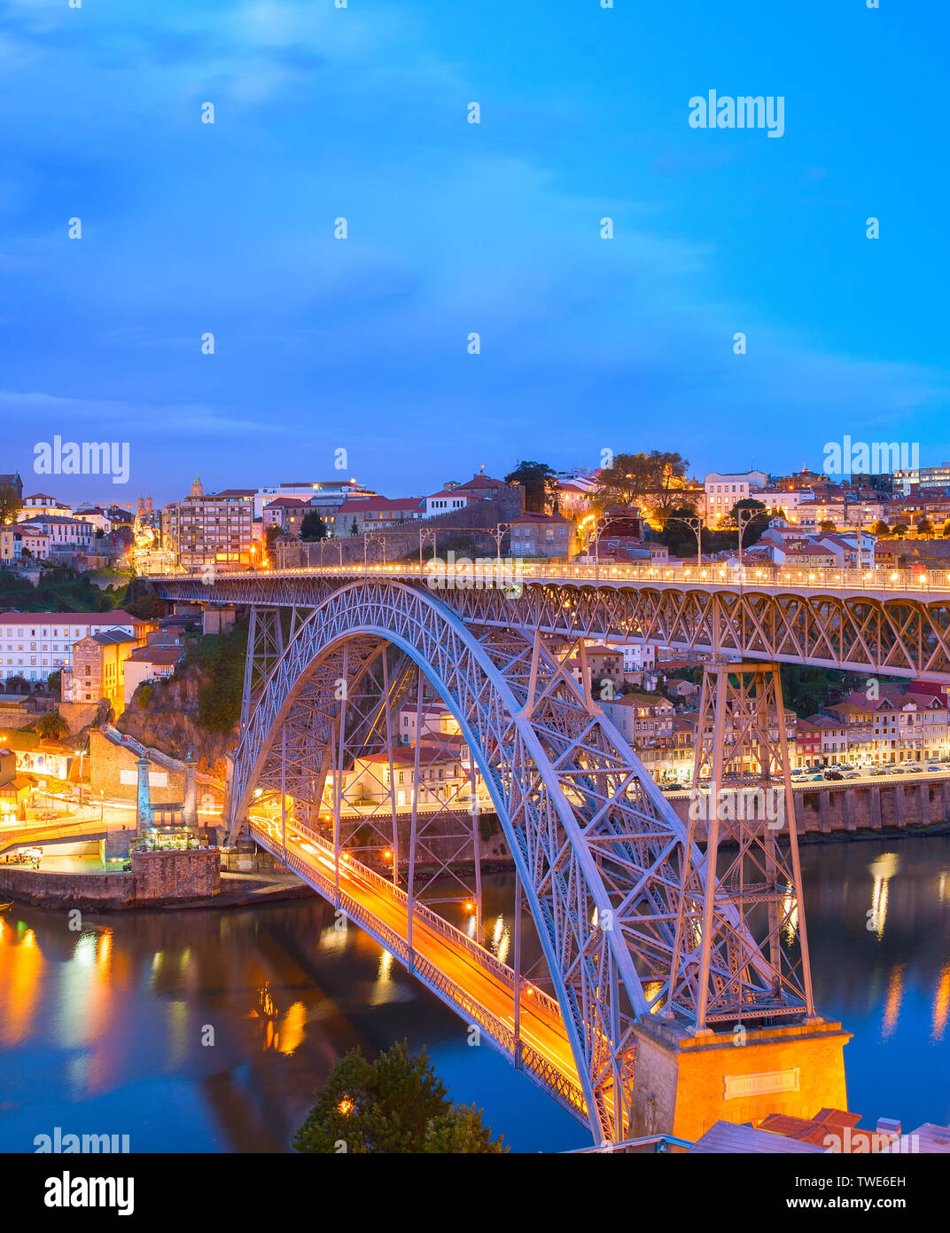 Illuminata di sera lo skyline di Porto con il famoso Dom Luis I Bridge riflettente nel fiume Douro, Portogallo Foto Stock