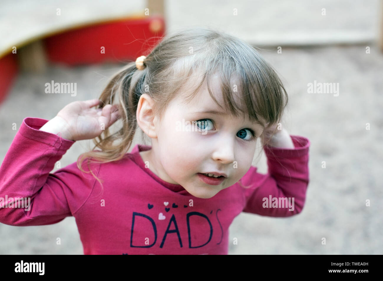 Funny bianco ragazza bambino faccia closeup ritratto sul parco giochi all'aperto sullo sfondo Foto Stock
