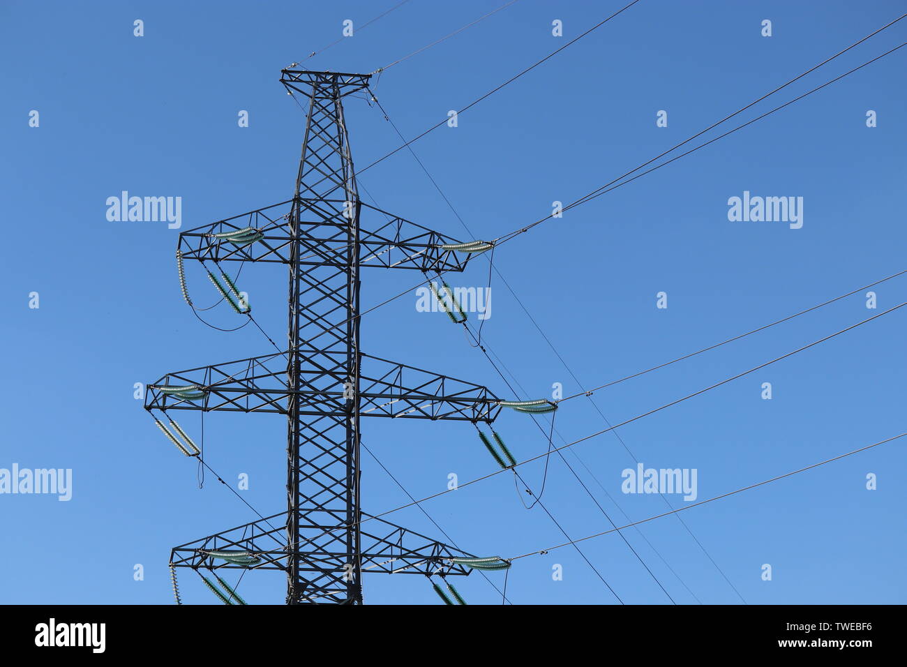 Alta tensione della linea di alimentazione supporti con fili elettrici isolati su blue sky. Linee di trasmissione di energia elettrica, alimentazione concept Foto Stock