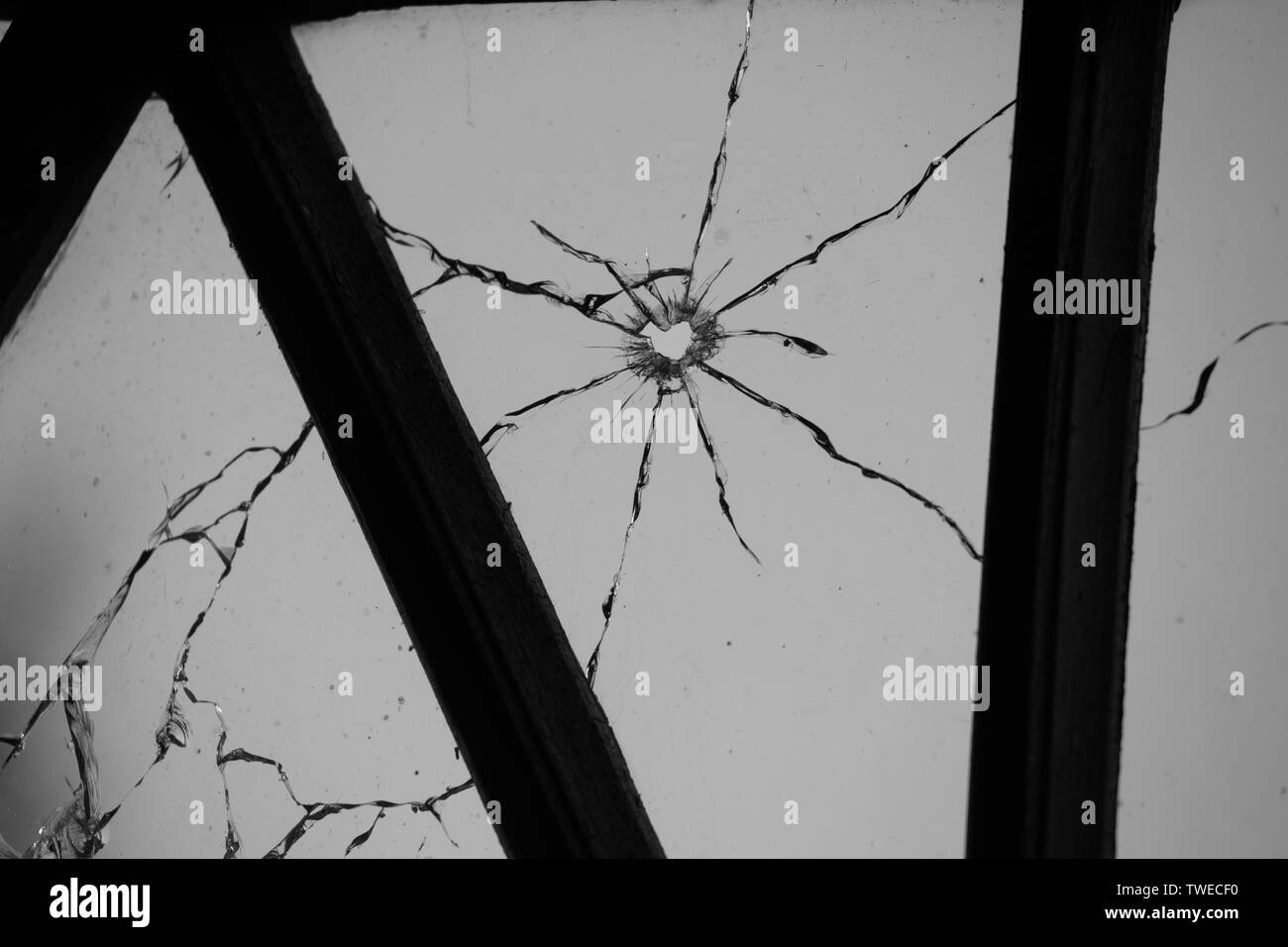 Rotto e rotto il vetro della finestra punzonato da una pistola bullet Foto Stock