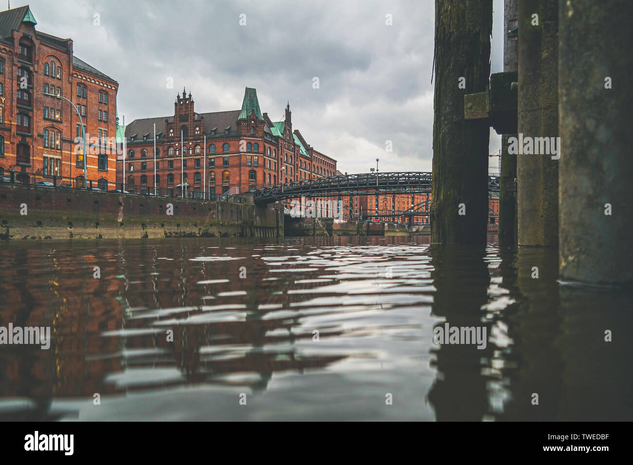 Basso angolo di vista canale e magazzini storico nel quartiere Speicherstadt di Amburgo contro il cielo velato Foto Stock