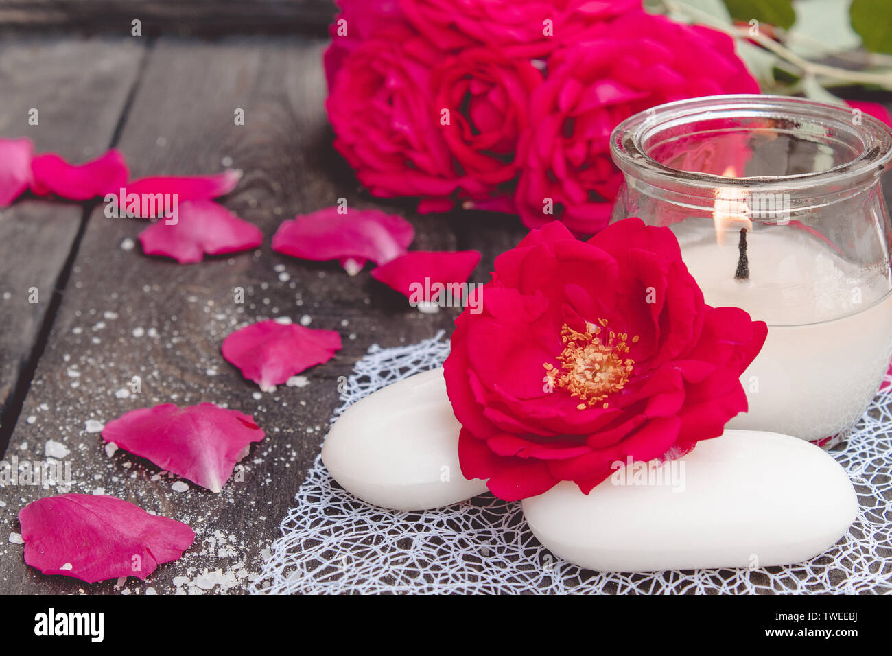 Cosmetici naturali sapone con rose rosse e candela a caldo sul legno scuro sfondo della spa Foto Stock