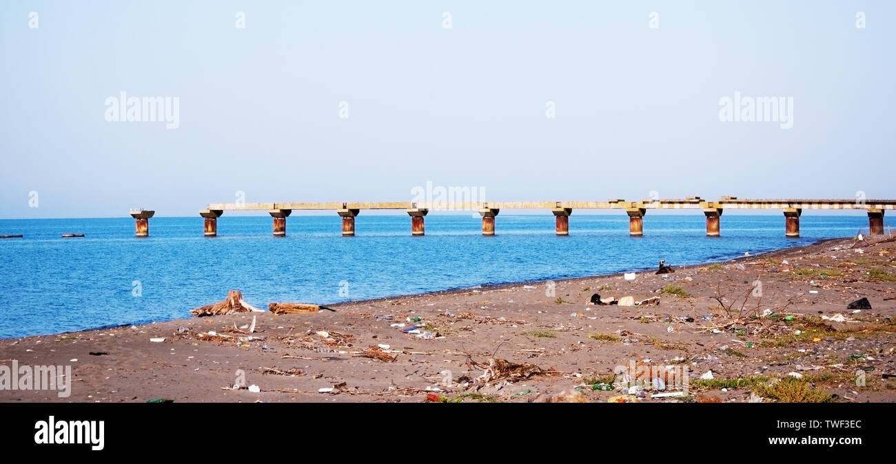 Vecchio rovinato pier e sporco e spiaggia del mar nero Foto Stock