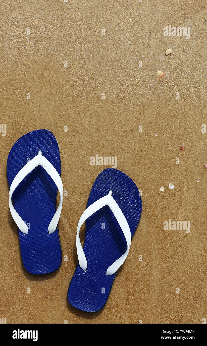 Pantofole blu sulla spiaggia sabbiosa Foto Stock