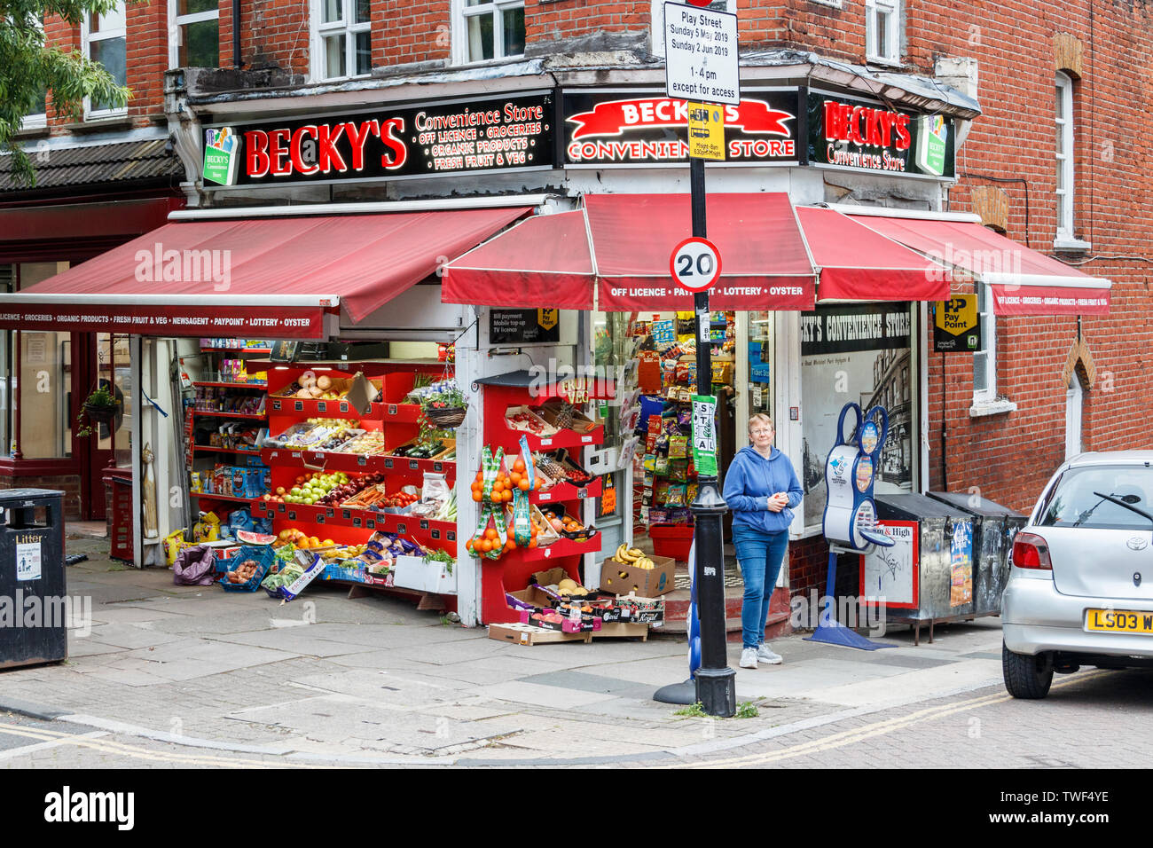 Una donna in piedi al di fuori di un locale convenience store o angolo shop, a nord di Londra, Regno Unito Foto Stock
