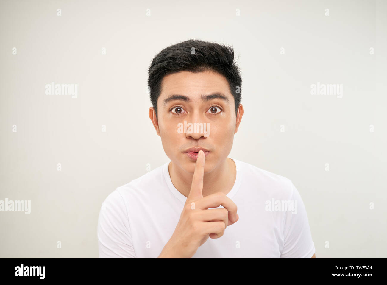 Uomo asiatico oltre isolato muro bianco che mostra un segno di silenzio gesto mettendo il dito in bocca Foto Stock