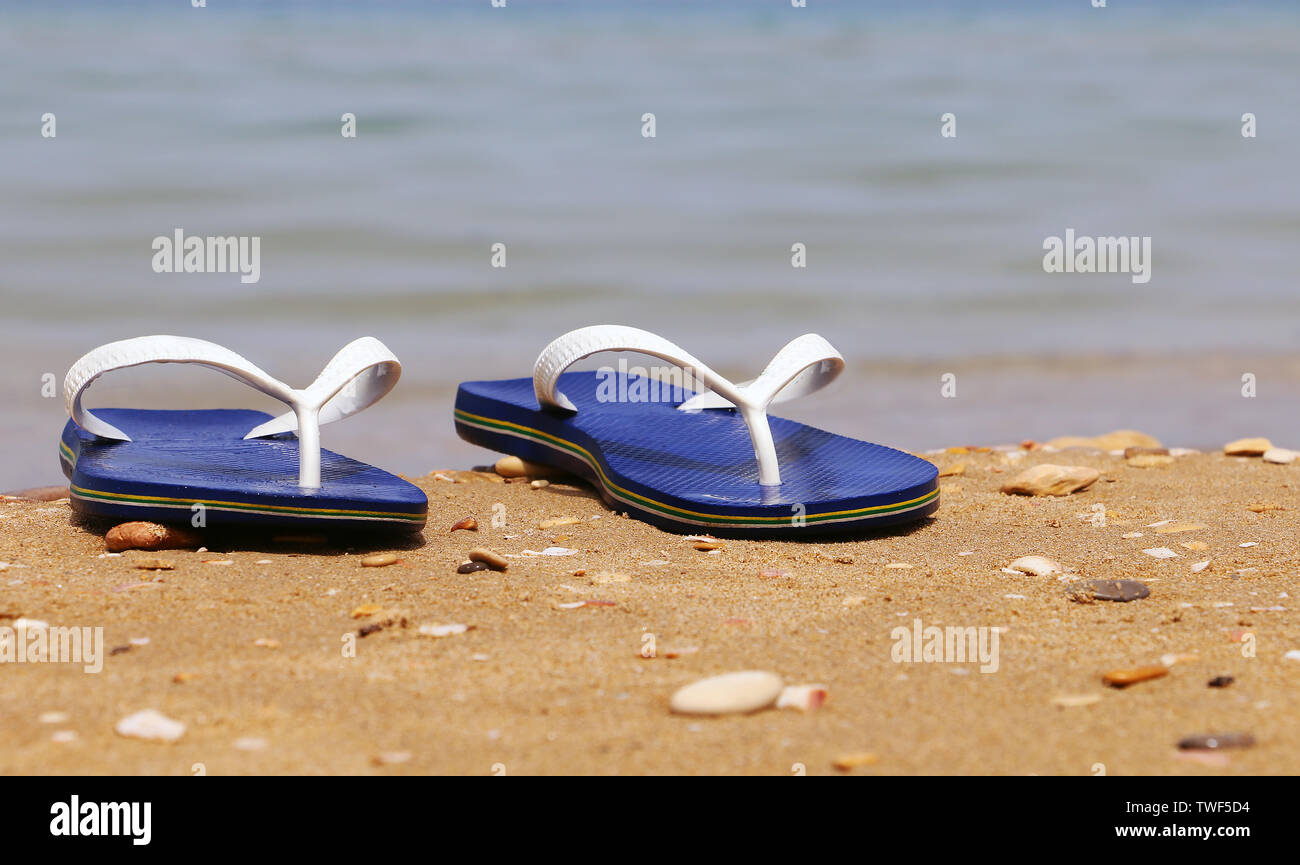 Pantofole blu sulla spiaggia sabbiosa Foto Stock