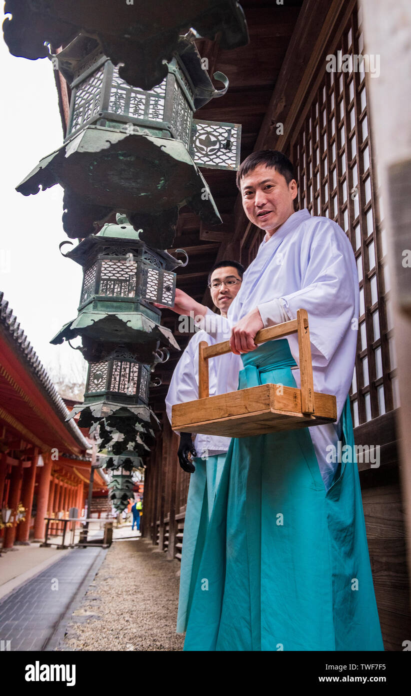 Angolo basso ritratto di monaci accensione lanterne al di Kasuga Taisha Sacrario di Nara in Giappone. Foto Stock