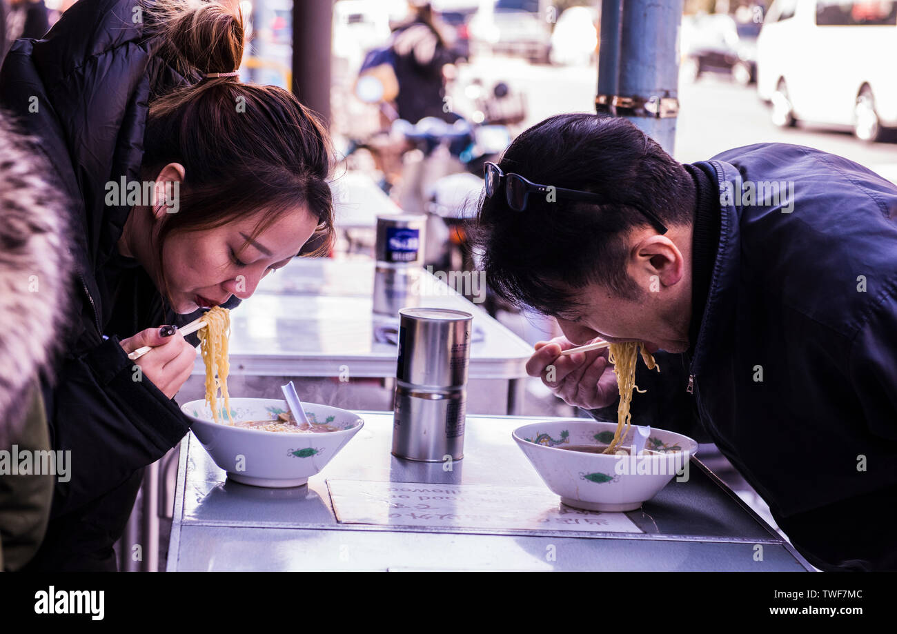 Due persone in un ristorante a mangiare una ciotola di noodles presso il mercato del pesce di Tsukiji a Tokyo in Giappone. Foto Stock