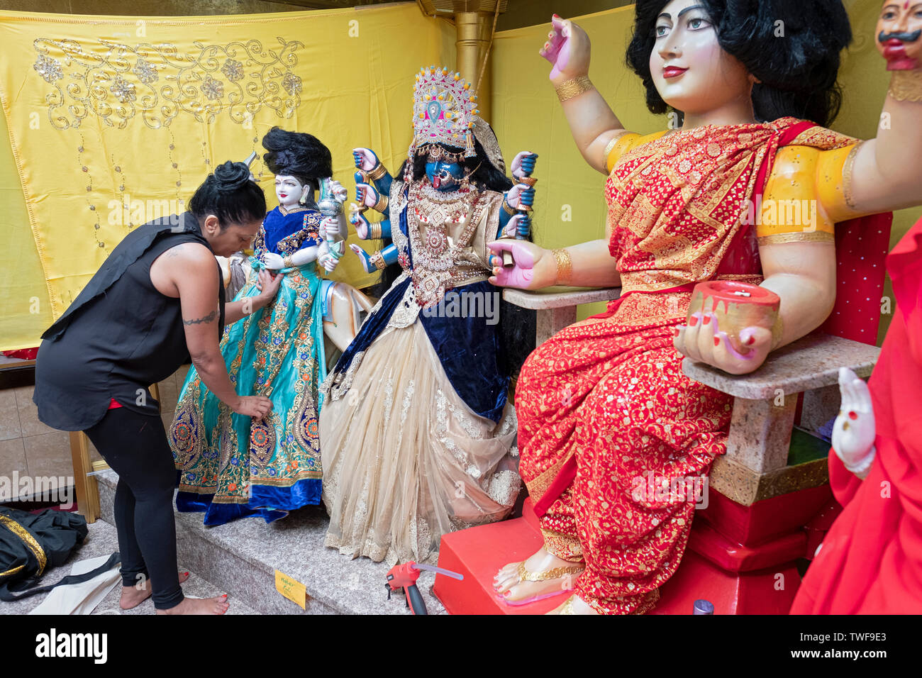 Come parte di un ringraziamento rituale, una pia donna progettato e installato nuovi vestiti sul tempio statue di divinità. In Ozone Park, Queens, NYC Foto Stock