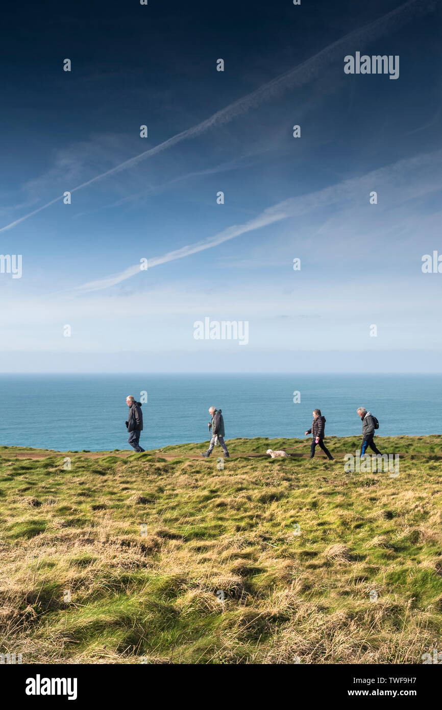 Un gruppo di escursionisti maturi e un cane a camminare lungo la costa sud occidentale il percorso sul North Cornwall coast. Foto Stock