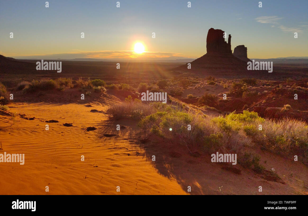 Il Monument Valley Navajo Tribal Park nel confine Arizona-Utah USA, a sunrise. Il sorgere del sole dietro le rocce rosse, cielo chiaro sfondo Foto Stock