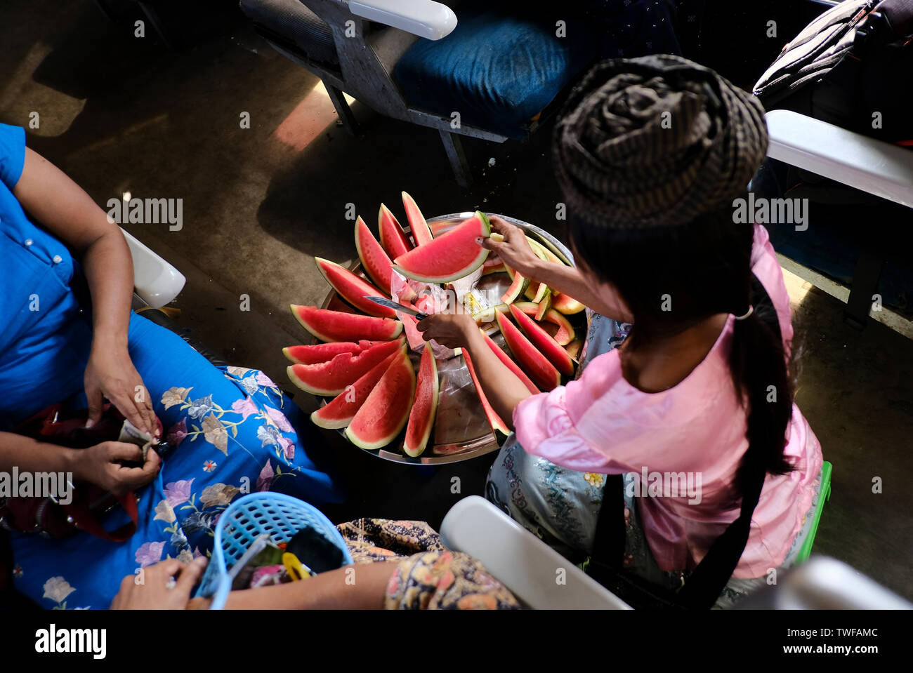 Una ragazza birmano vende fresco tagliato dell'anguria su un treno dei pendolari nella città di Yangon. Foto Stock