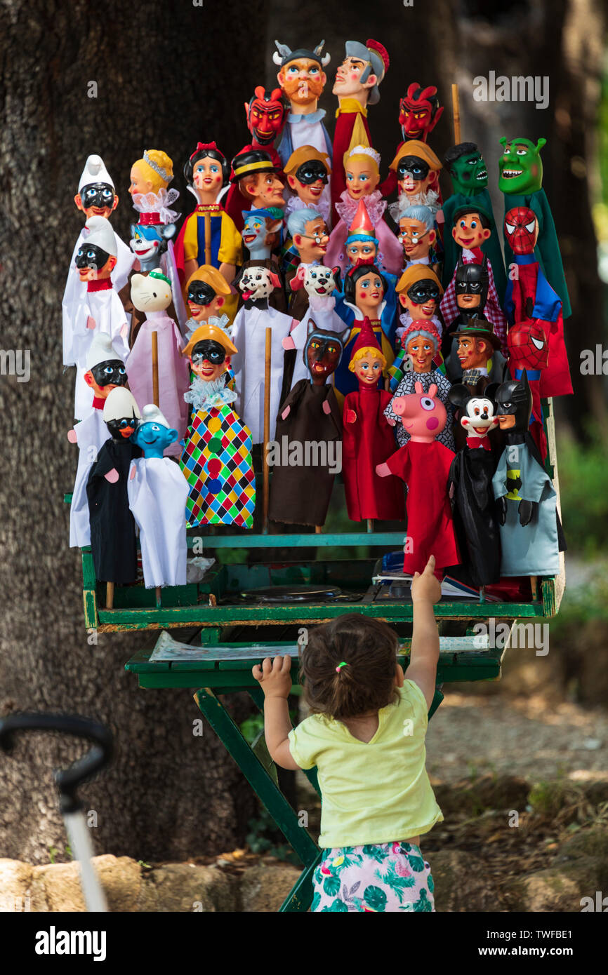 Una bambina punti verso l'alto alle colorate marionette a mano su una fase di stallo nel colle del Gianicolo distretto. Foto Stock