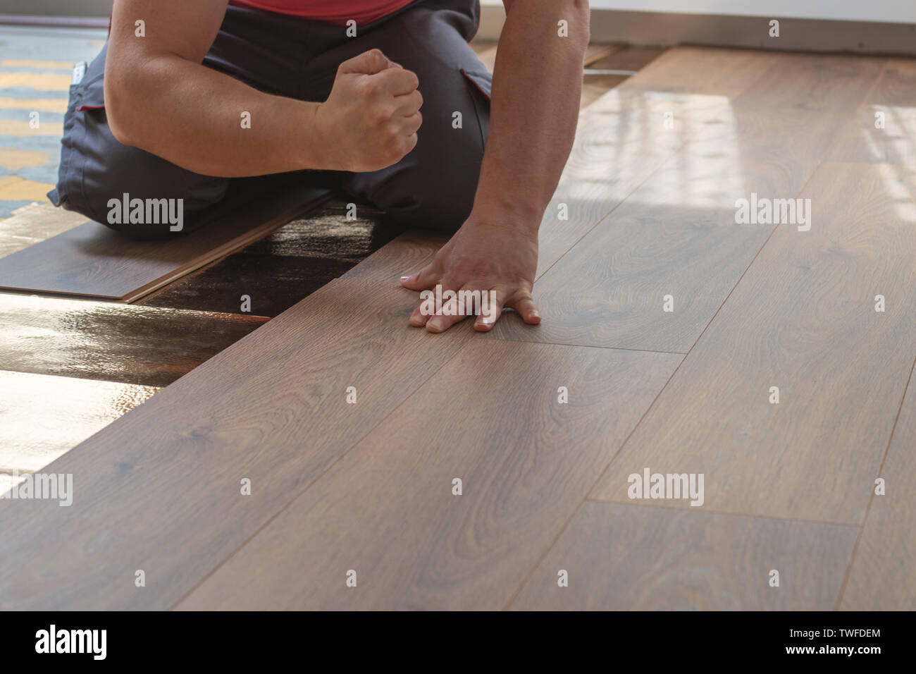 Mani di tuttofare sbattere il laminato Plank per la posa del pavimento in laminato Foto Stock