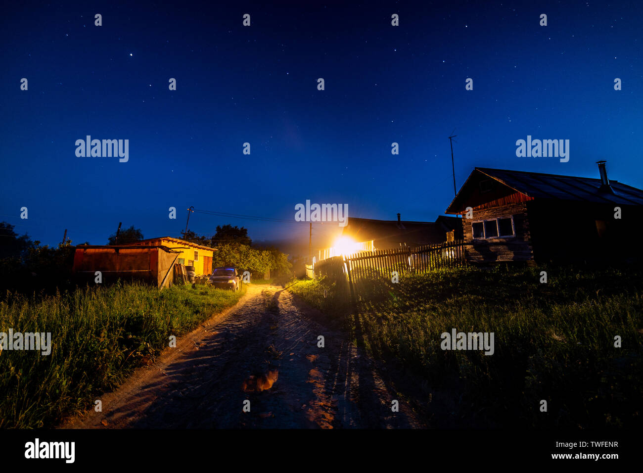 Cielo stellato su una casa di villaggio in estate. Casa in legno con una lampadina sulla luce di ingresso. La Russia Foto Stock