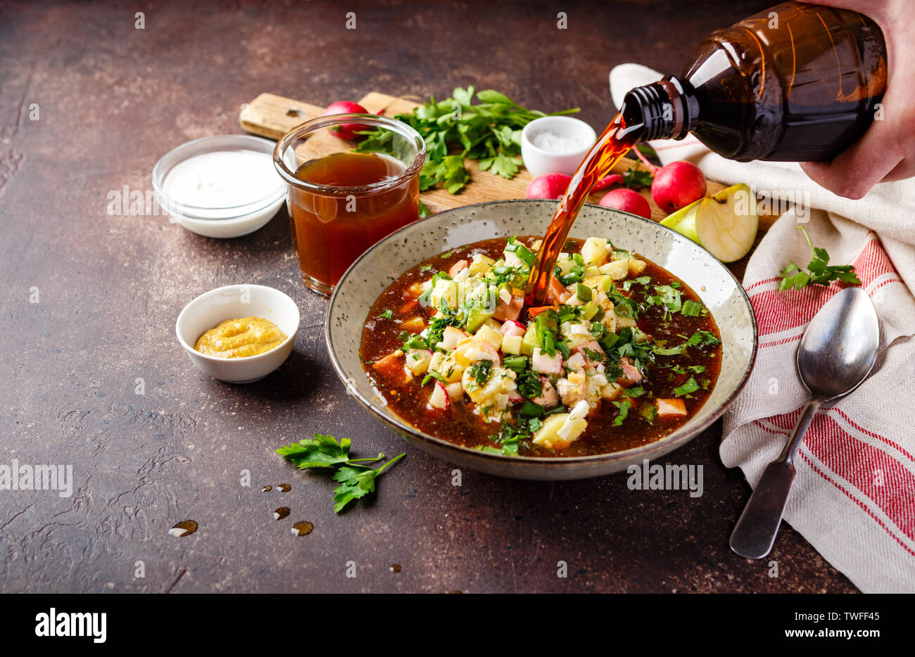 Freddo zuppa russa Okroshka con salsiccia, verdure e kvass nella ciotola e materie prime sul tavolo scuro Foto Stock