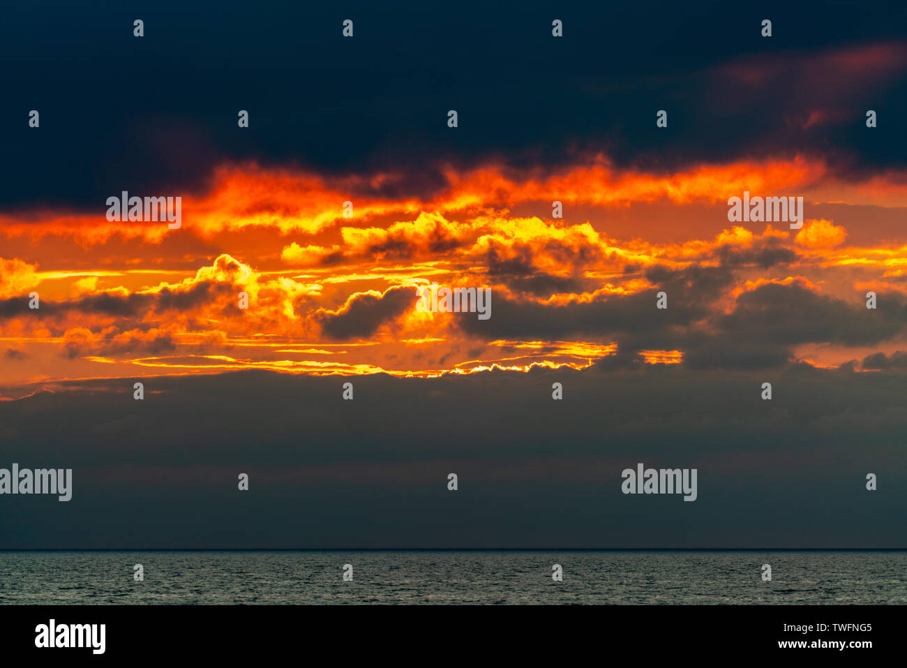 Burning skies con orange nuvole come il fuoco nel cielo poco dopo il tramonto al mare Foto Stock
