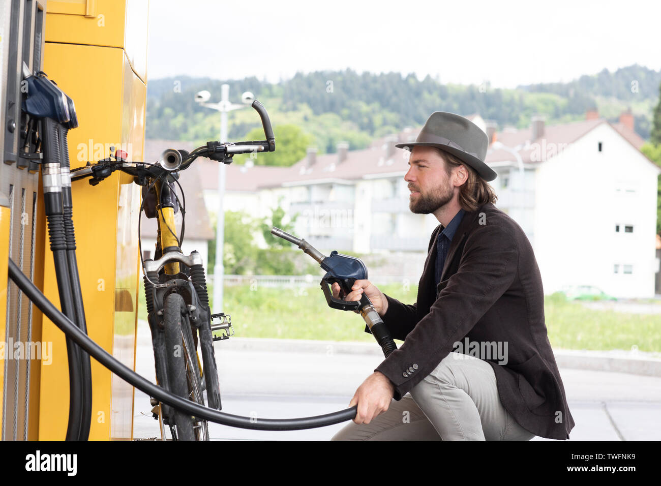 L'uomo il rifornimento di una bicicletta motorizzata in corrispondenza di una stazione di benzina Foto Stock