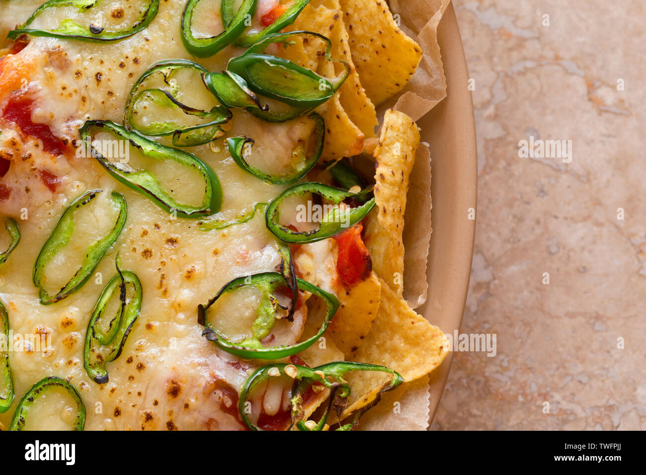 Una pietanza fatta in casa di nachos che contiene tortilla chips, salsa calda, formaggio Cheddar grattugiato e fette di chilis verde che sono state cotte sotto una griglia Foto Stock