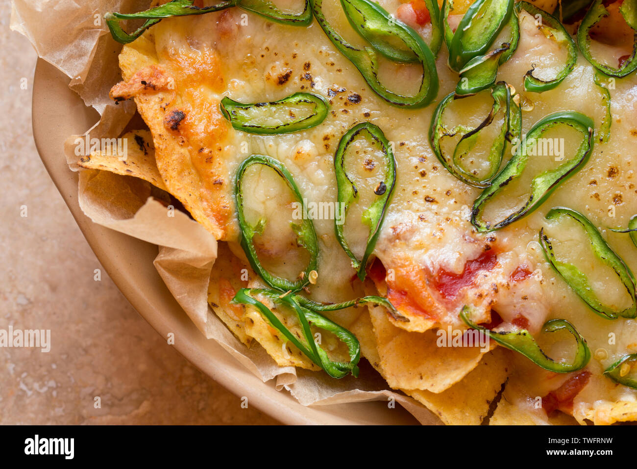 Una pietanza fatta in casa di nachos che contiene tortilla chips, salsa calda, formaggio Cheddar grattugiato e fette di chilis verde che sono state cotte sotto una griglia Foto Stock