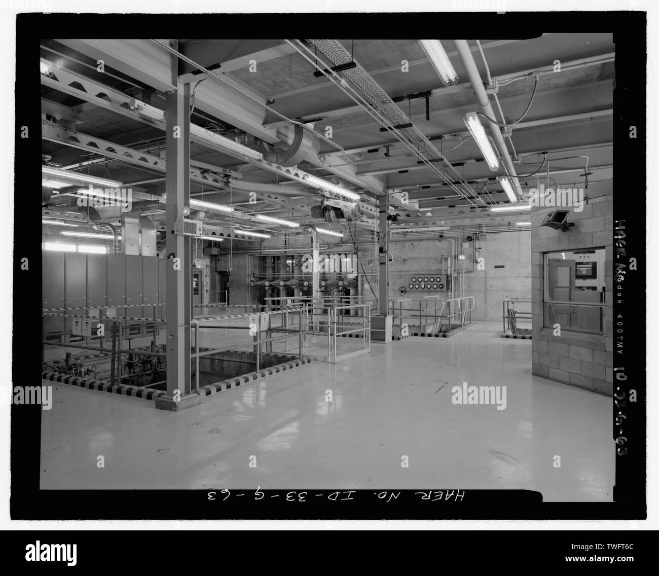 Acqua di processo edificio, TRA-605, interno. Primo piano. La telecamera è in angolo sud-est e si affaccia a nord-ovest. Sala di controllo a destra. Gru monorotaia è sul pavimento portelli e aperture nel pavimento. Sei volantini di valvola lungo la parete più lontana in centro a sinistra vista. Guarnizione serbatoio è sul lato opposto della parete; acqua di processo tubi sono sotto le ruote della valvola. Nota cordoli attorno alle aperture nel pavimento. Negativo INL No.46-26 HD-3.; Mike gru, fotografo, 2-2005 - Idaho National Engineering Laboratory, Test Area reattore, materiali e test di progettazione di reattori, Scoville, Butte County, ID Foto Stock