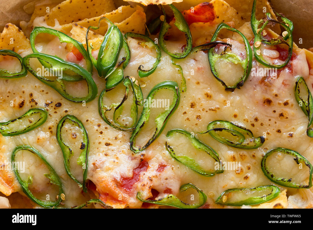 Una pietanza fatta in casa di nachos che contiene tortilla chips, salsa calda, formaggio Cheddar grattugiato e fette di chilis verde che sono state cotte sotto una griglia Foto Stock