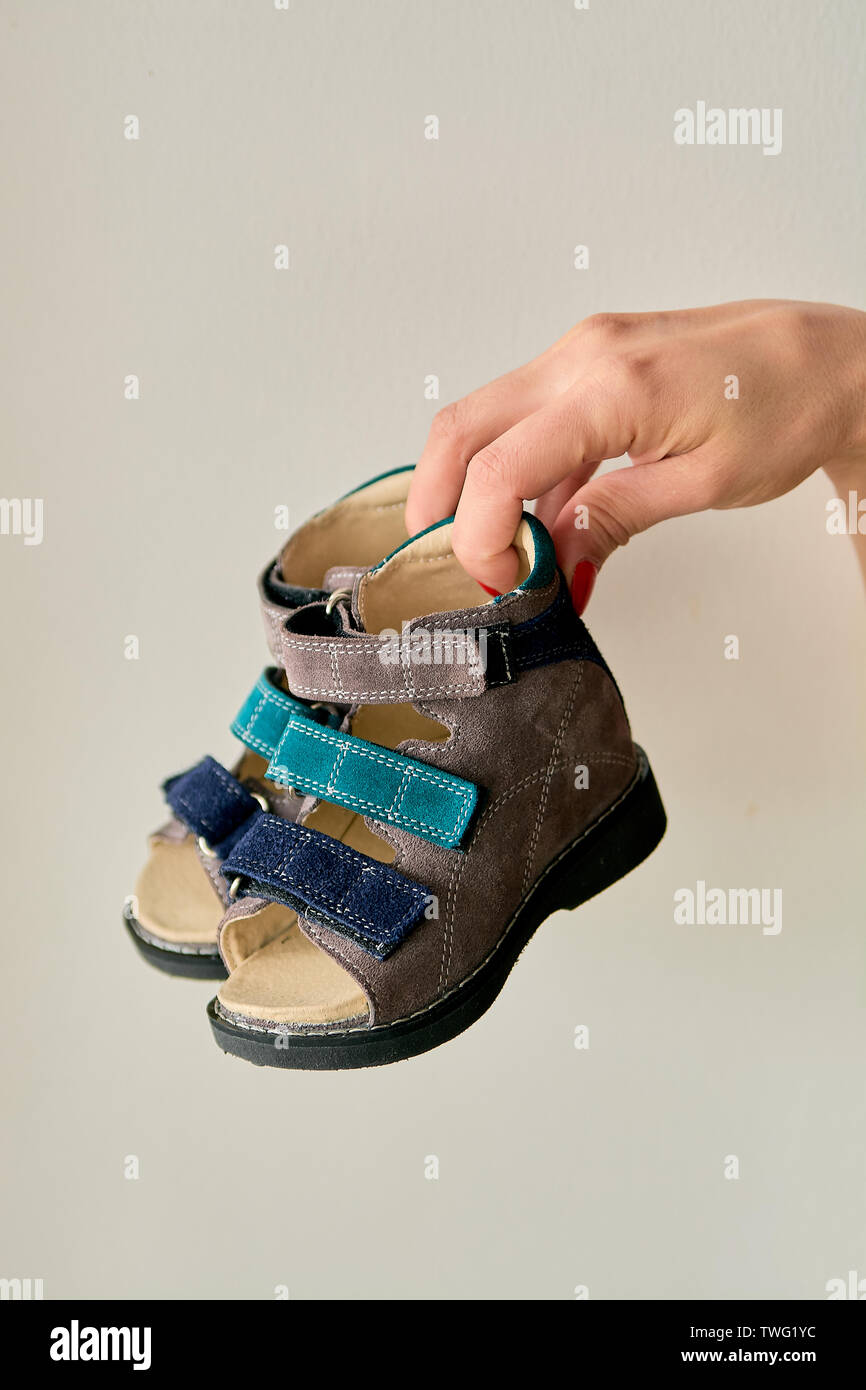 Femmina è holding close-up di una speciale per bambini scarpa ortopedica  sandali in vera pelle. Scarpe comode isolato su sfondo chiaro con c Foto  stock - Alamy