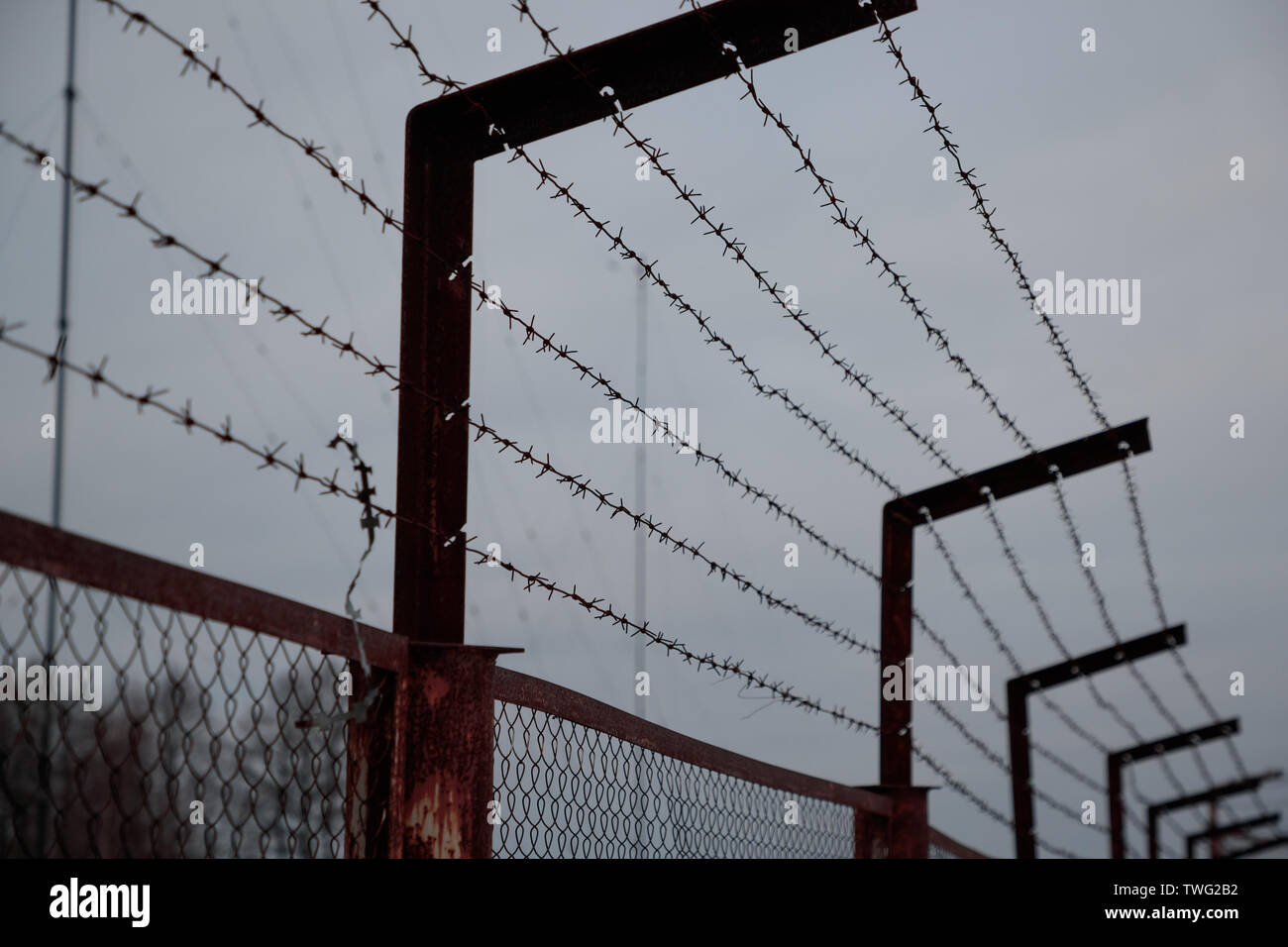 Filo spinato sulla recinzione in tempo nuvoloso Foto Stock