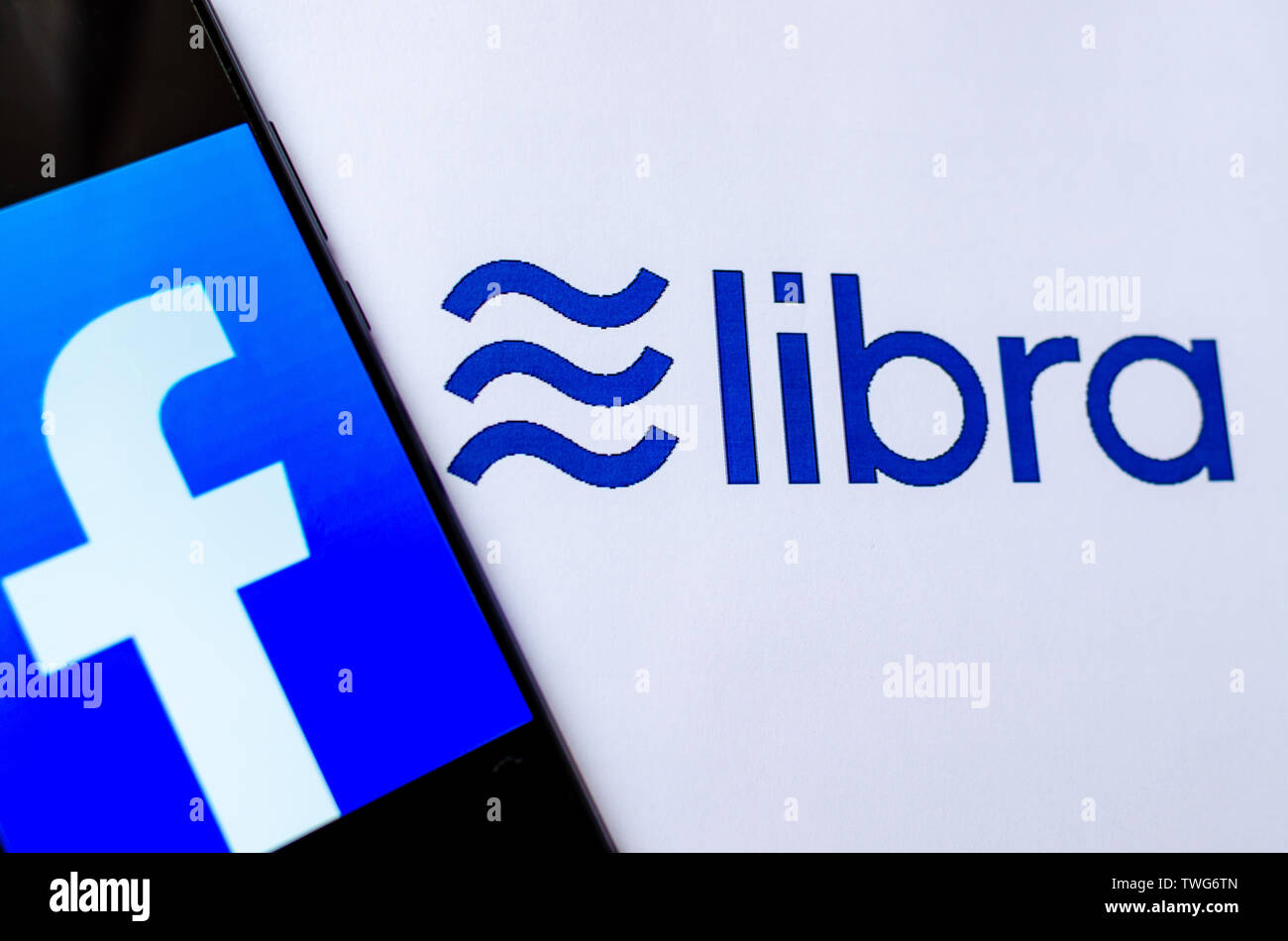 Facebook bilancia è una nuova moneta crypto. La foto di smartphone con logo di Facebook su schermo tge e la Libra logo sul broshure accanto ad essa. Foto Stock