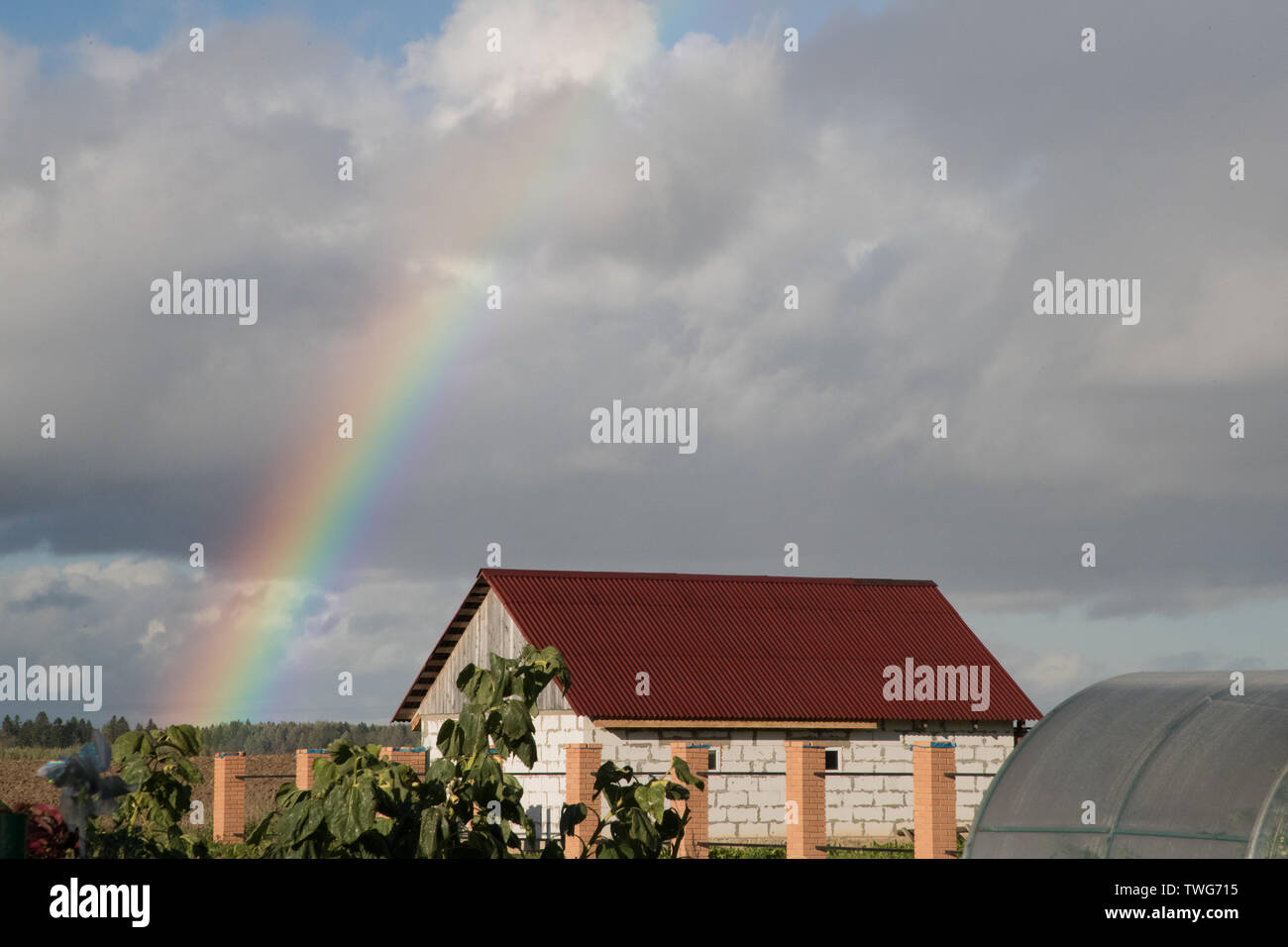 Rainbow su una casa privata nel centro di nuvole grigio Foto Stock