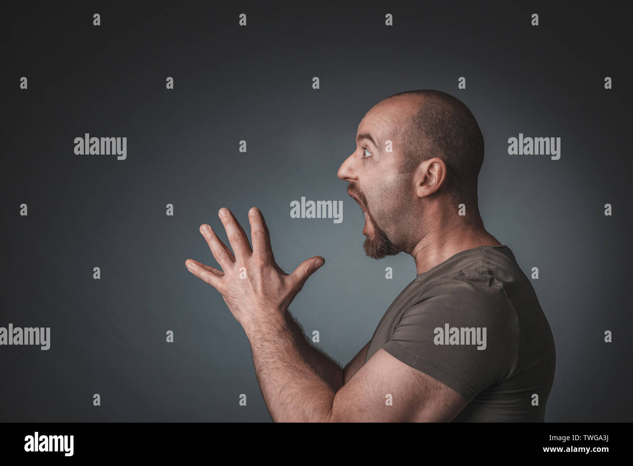 Ritratto in studio di un uomo con espressioni di sorpresa mani giunte, vista di profilo. Foto Stock