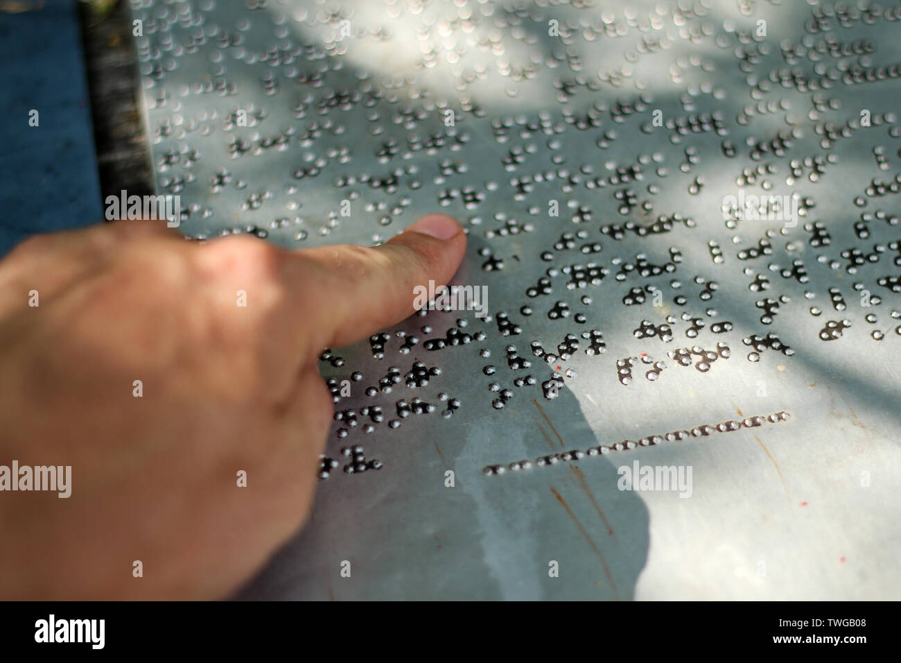 Un dettaglio del testo in alfabeto Braille. Il dettaglio delle informazioni di un segno. Il dito è la lettura di adesso. Foto Stock