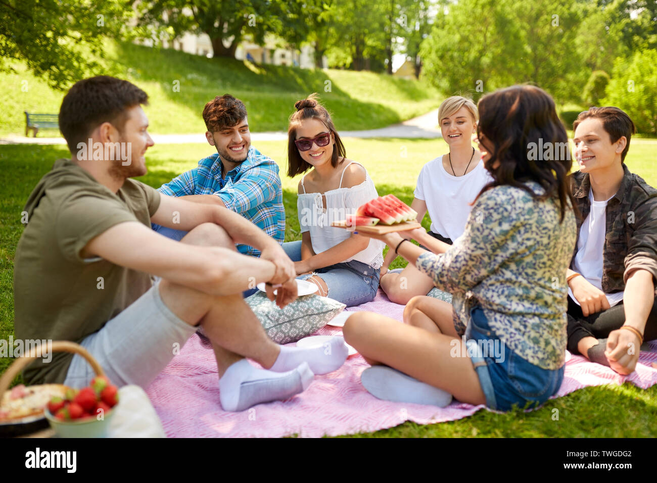 Happy amici mangiando anguria a picnic estivo Foto Stock