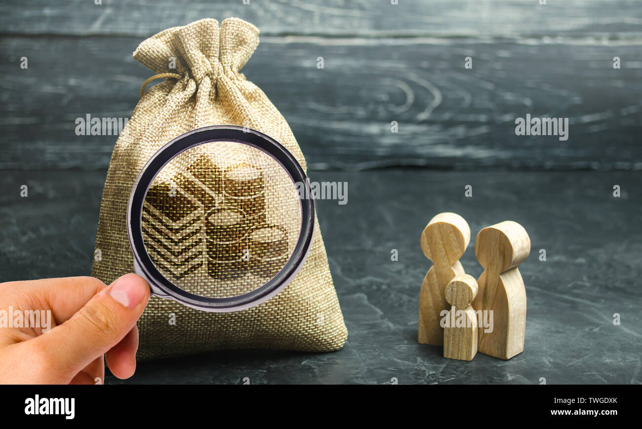 Miniatura in legno figurine famiglia stare vicino a un sacco di denaro. Il concetto di risparmio. Pianificazione del bilancio. Distribuzione degli utili. Gestione finanziaria. Accu Foto Stock