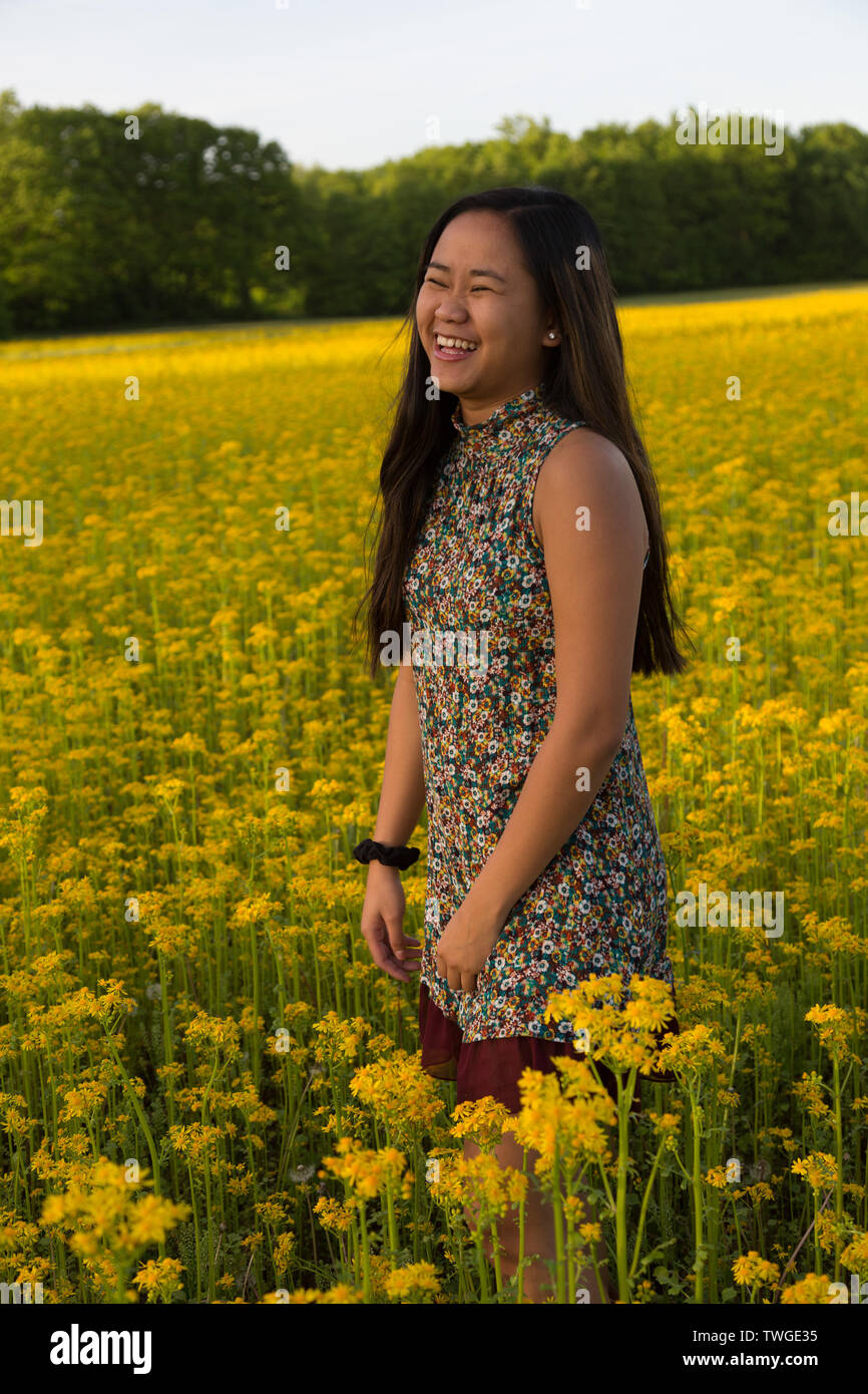 Una bella ragazza adolescente ride mentre in un campo di giallo in Fort Wayne, Indiana, Stati Uniti d'America. Foto Stock